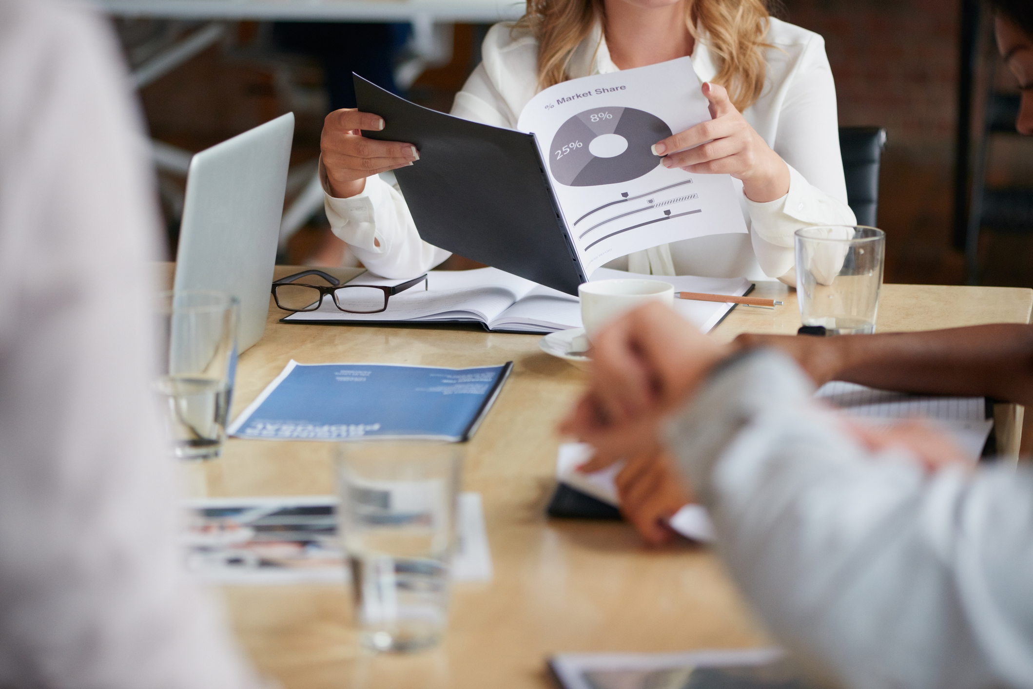 Colleagues around a table reviewing printed performance reports in a meeting